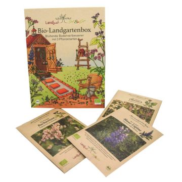Verpackung der Bio-Landgartenbox mit drei Beuteln Samen für blühende Bodenverbesserer; zeigt Gartenszene mit Hütte, Stuhl und Pflanzen bei Sonnenuntergang; enthält Buchweizen, Blauer Lein und Ölrettich.