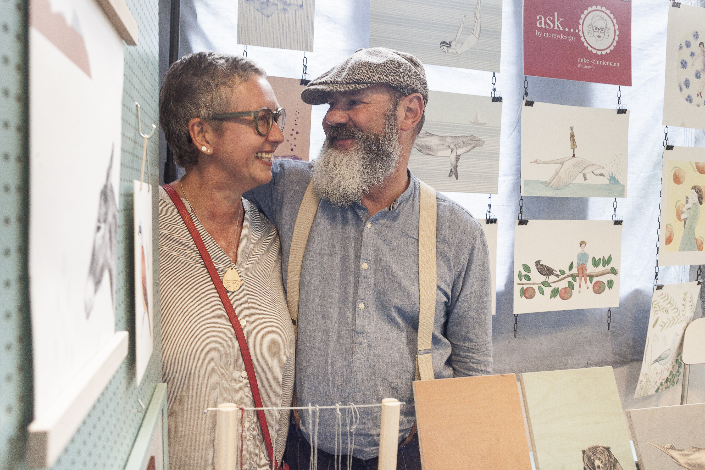Fotografie des Illustratoren Paares, das Bild wurde in Ihrem Atelier aufgenommen, im Hintergrund sieht man verschiedene Bilder.