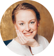 Annika Koch mit hellem Haar lächelt, den Kopf auf eine Hand gestützt, vor einem goldfarbenen Hintergrund. Sie trägt ein weißes Oberteil. Shop-Management