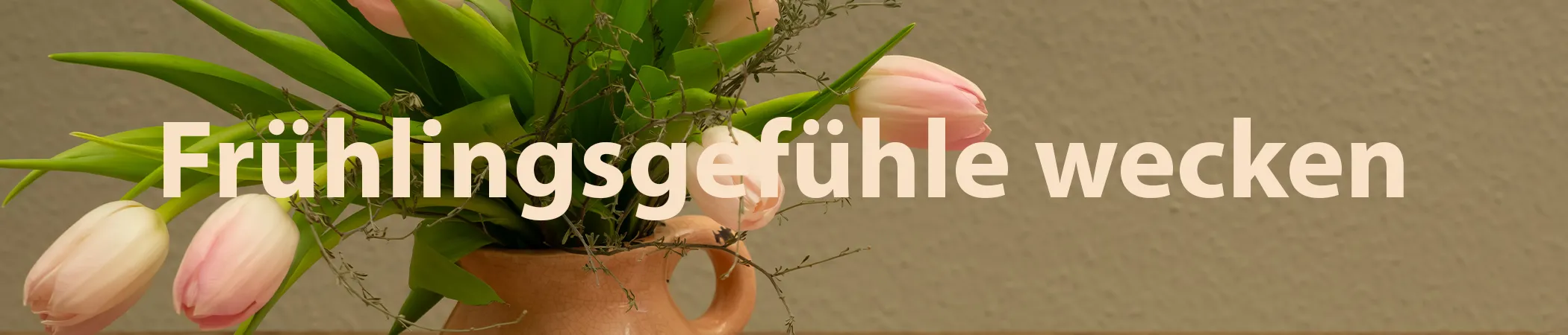 Ein keramischer Krug mit rosa Tulpen und grünen Blättern vor einer beigefarbenen Wand. Der Text "Frühlingsgefühle wecken" überlagert das Bild mittig in großer, weißer Schrift.