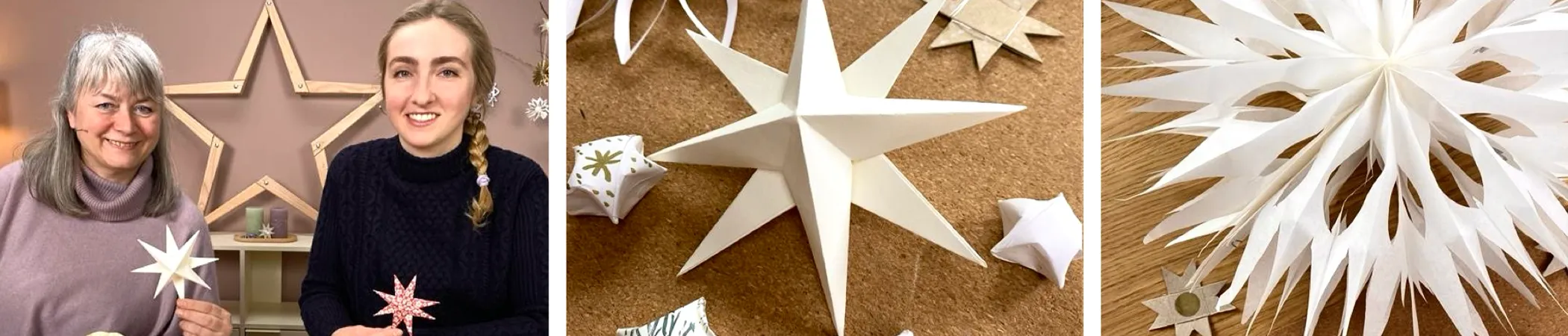 Zwei Personen halten weiße und rote Bastelsterne, umgeben von weiteren weißen Sternornamenten auf einem Tisch. Hintergrund zeigt große Holzsterne an der Wand.