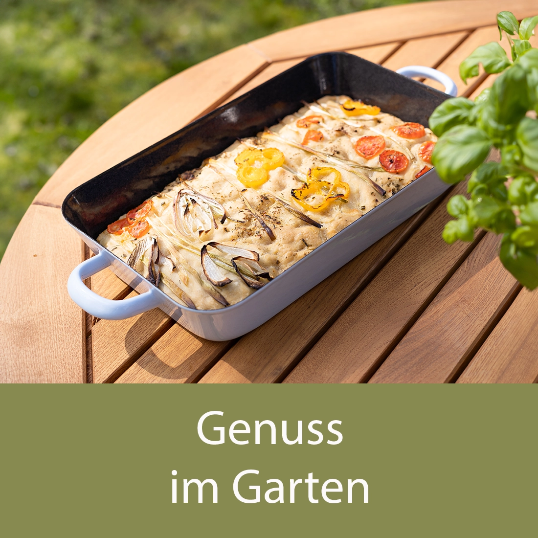 Weiße Auflaufform mit Gemüsefladen auf einem Holztisch im Garten. Im Vordergrund Basilikum, darunter Text: Genuss im Garten. Bild verlinkt zur Kategorie.
