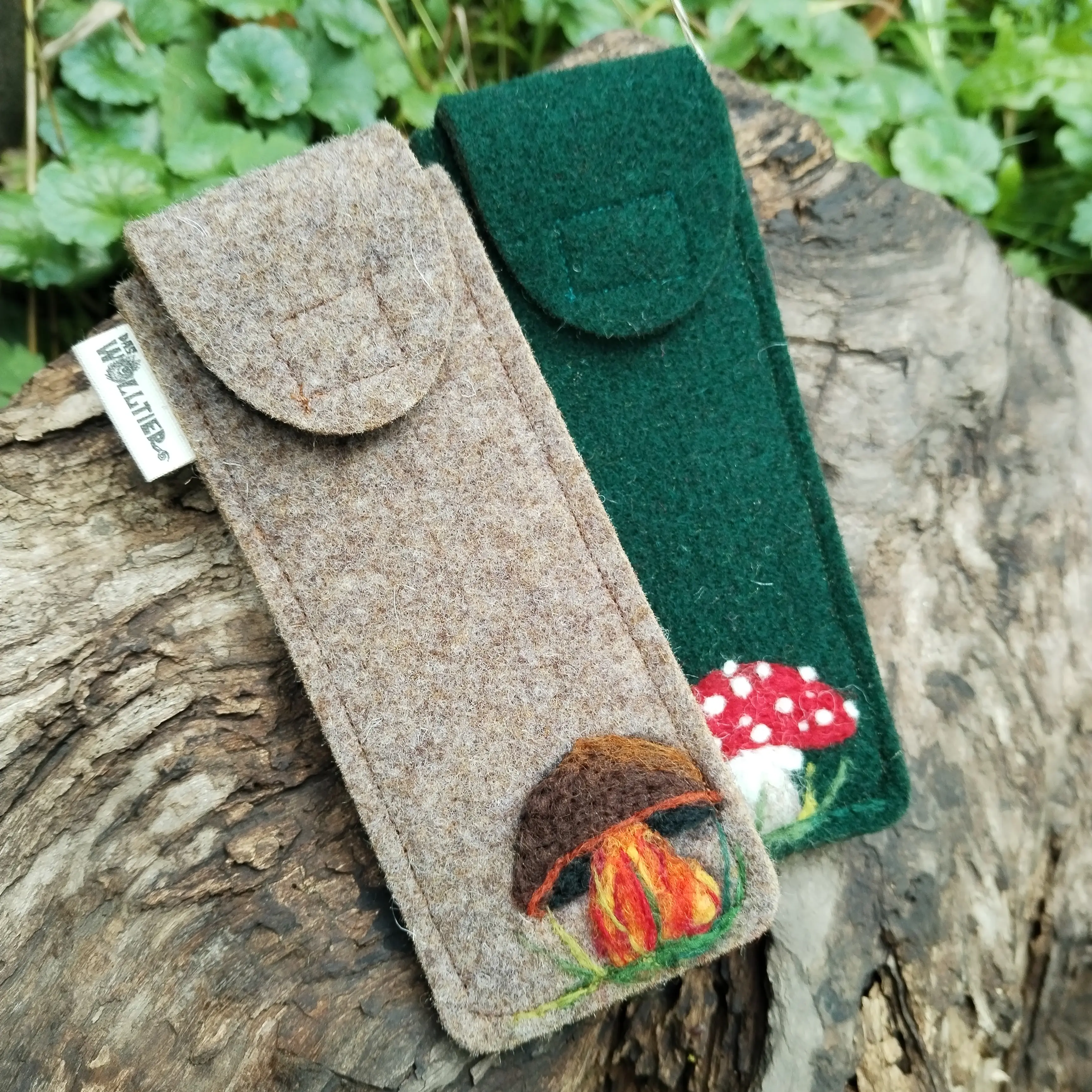 Filzetui mit aufgesticktem Pilzmotiv; das Etui ist aus grauem Wollfilz gefertigt und zeigt einen Steinpilz und das andere Etui mit grünem Wollfilz zeigt einen roten Fliegenpilz.